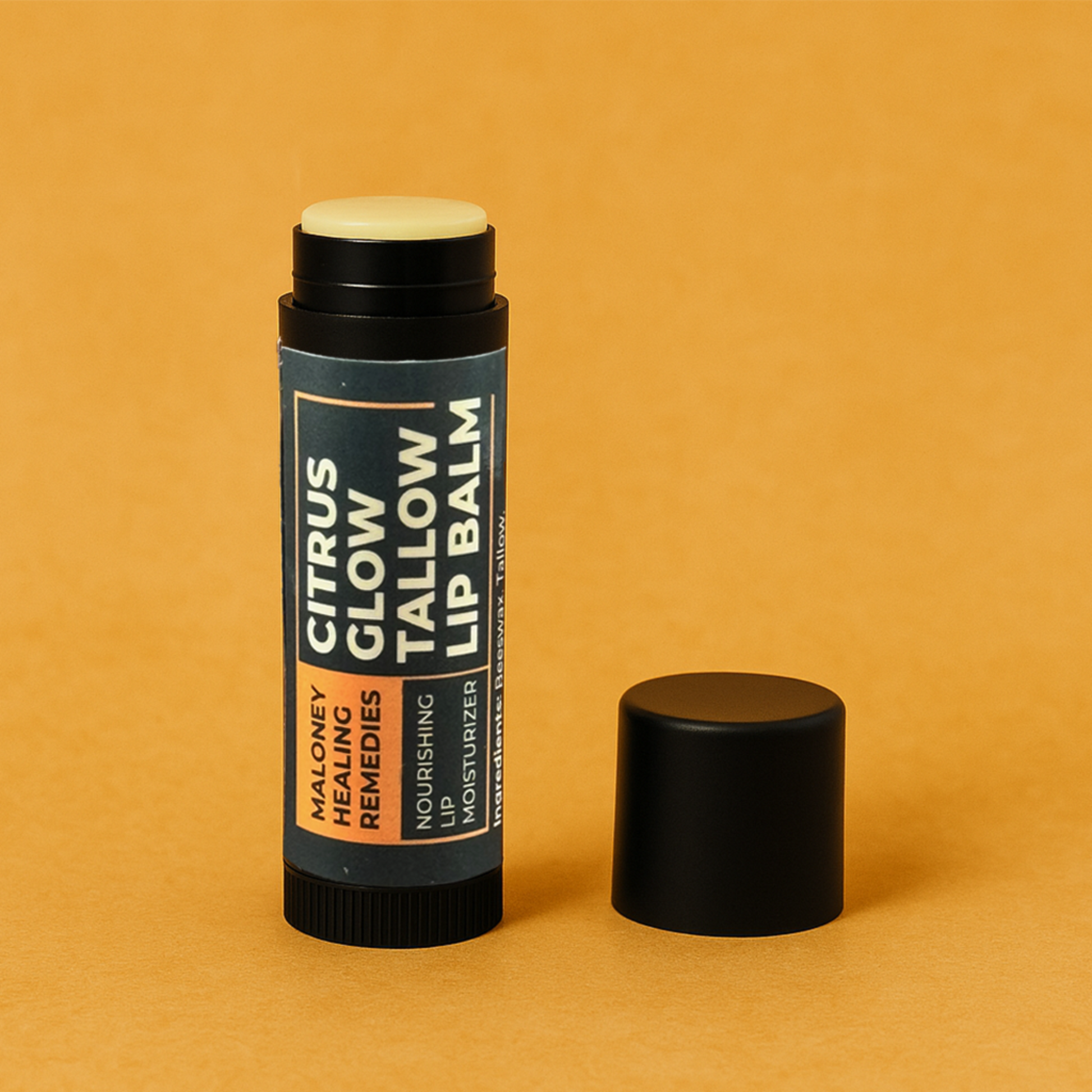 Black tube of Citrus Glow Tallow Lip Balm, an all natural lip balm, standing upright with the cap off on a warm ochre background, showing the product's label and natural balm color.