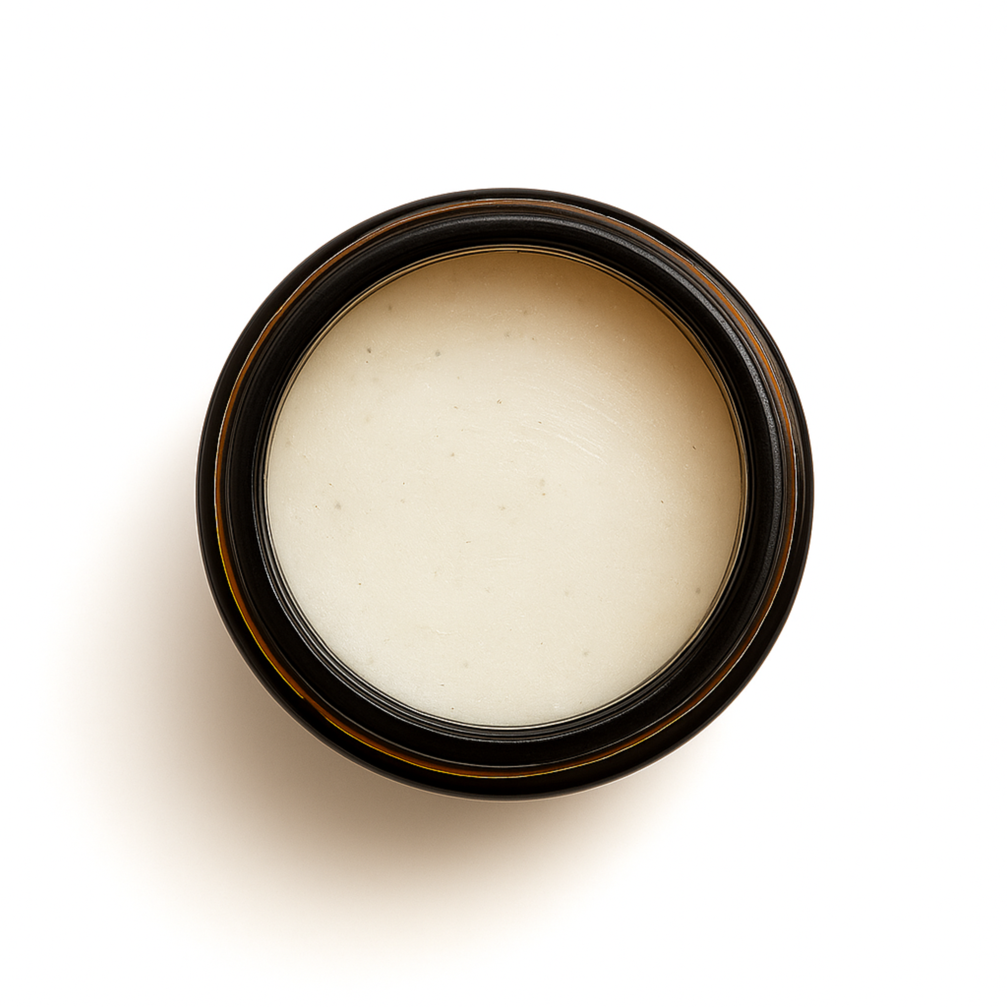 Top-down view of an open amber glass jar filled with a smooth, pale zinc-tinted balm. Maloney Healing Remedies Sedona Solar Shield, formulated with grass-fed tallow and non-nano zinc oxide