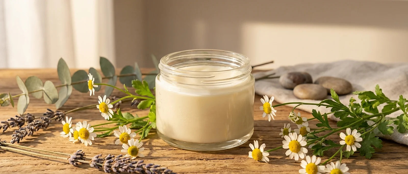Glass jar of creamy white grass-fed beef tallow balm on natural wooden surface with fresh botanical elements