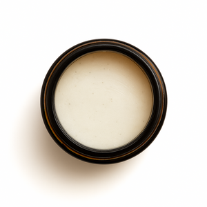 Top-down view of an open amber glass jar filled with a smooth, pale zinc-tinted balm. Maloney Healing Remedies Sedona Solar Shield, formulated with grass-fed tallow and non-nano zinc oxide